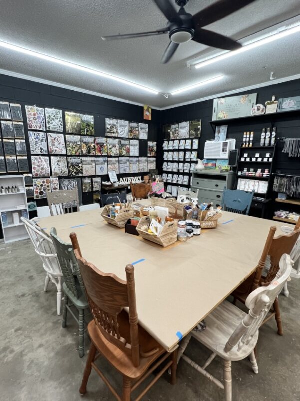 Woman painting a colorful abstract floral canvas during an art class.