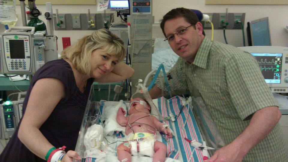 Woman smiling while holding a coffee mug, seated near a window.
