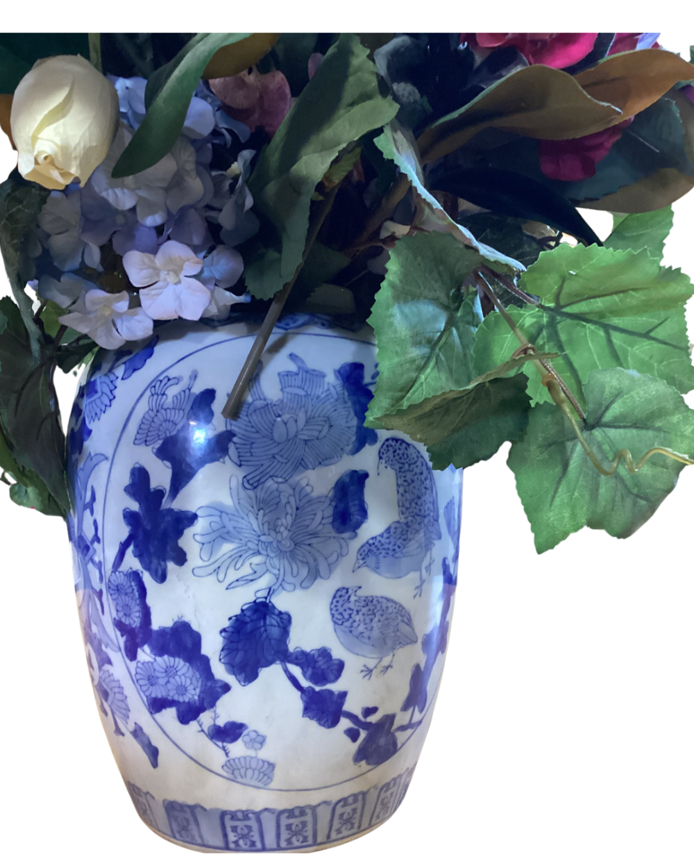 Blue and white porcelain pitcher with a mixed bouquet of artificial flowers.