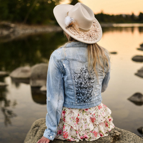 Hand-burned and painted hat by Wild & Rogue Boutique worn outdoors by a lake.