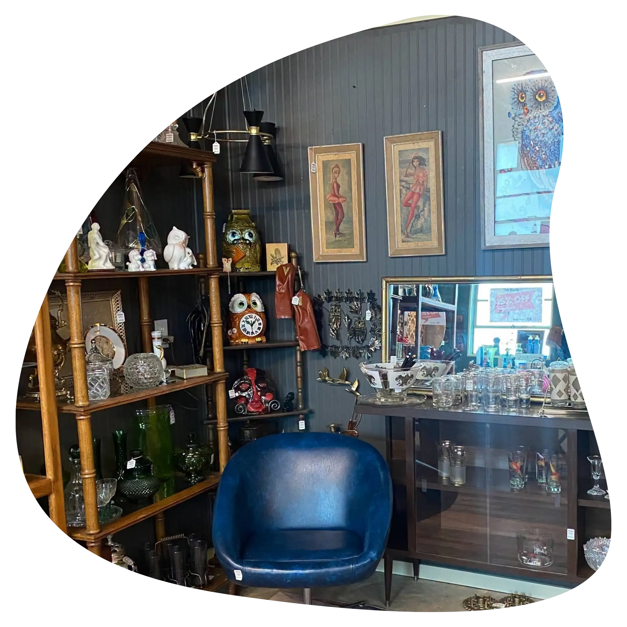 a vendor booth at Vintage Blue with a blue vintage chair and lots of eclectic collectibles on shelves behind it