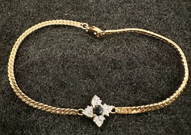 Gold tone herringbone bracelet with blue and clear crystal center