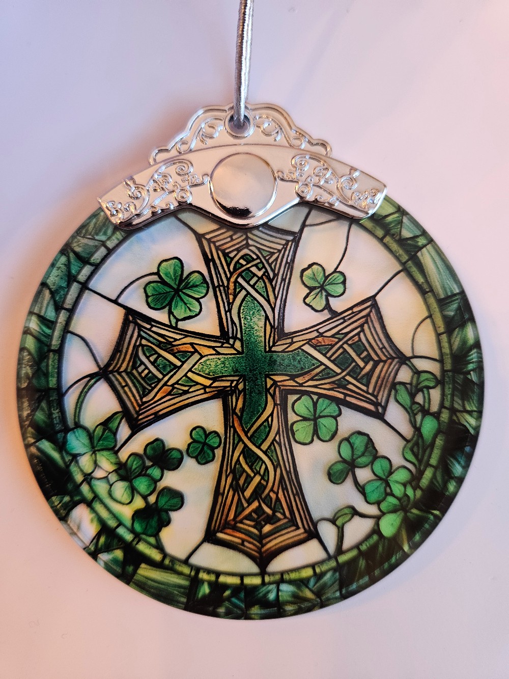 This Celtic cross suncatcher features vibrant green and brown glass panels detailed with shamrocks and intricate knotwork