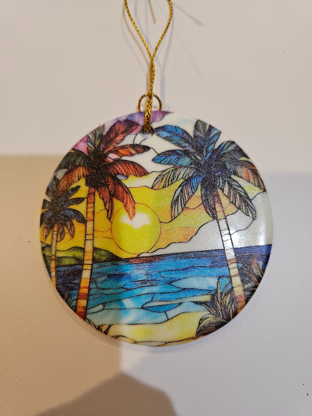 tropical-themed suncatcher featuring a printed sunset scene with palm trees.
