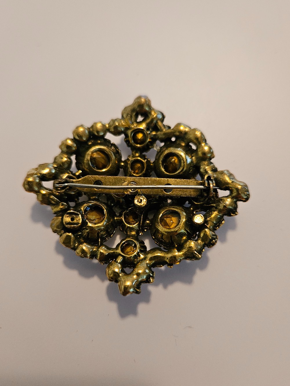 vintage brass-tone brooch features a dense cluster of clear glass rhinestones