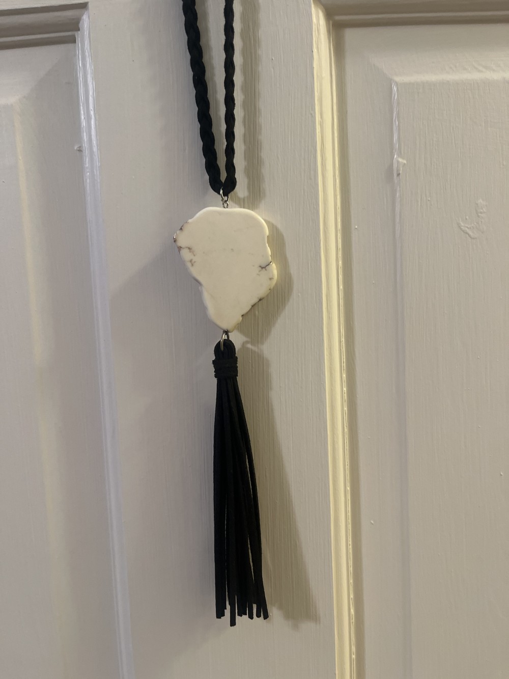 This pendant necklace features a unique, irregularly shaped stone resembling a white marble or howlite centerpiece.