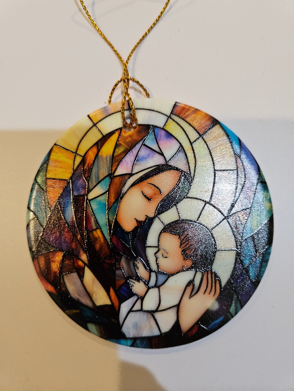 Stained glass-style ornament image of Mary holding Baby Jesus.