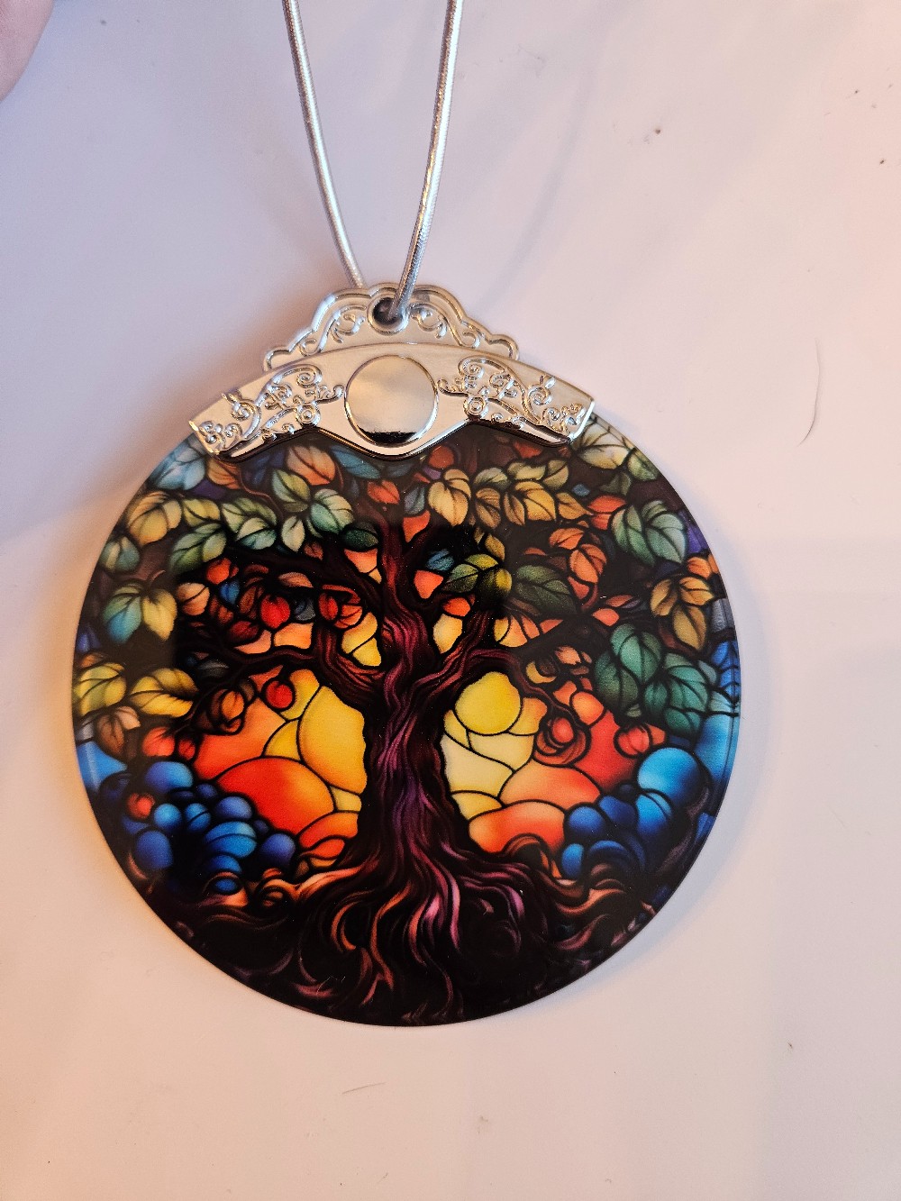 This Jocidea Tree of Life ornament features a vibrantly colored faux stained glass design printed on a 3-inch round disk