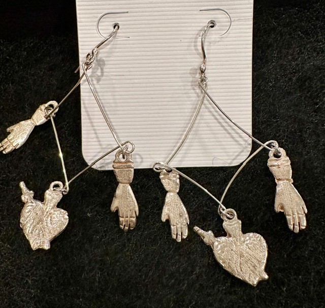 Silver tone Milagro-inspired dangle earrings with sacred heart and hand charms.