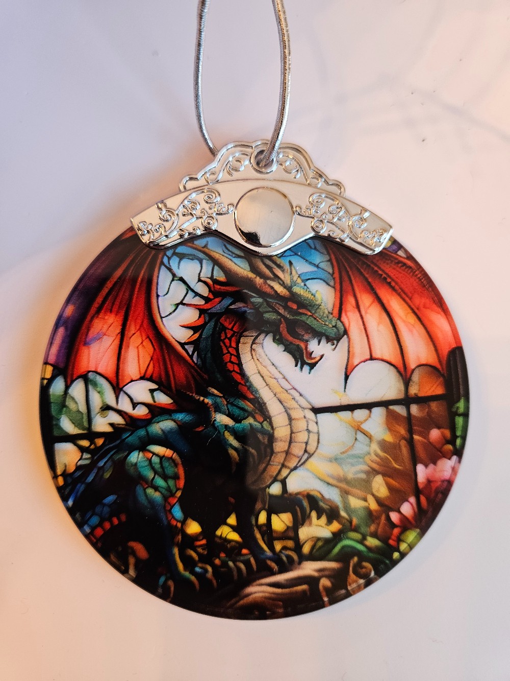 Stained glass dragon ornament features a vibrant green and red mythical beast.