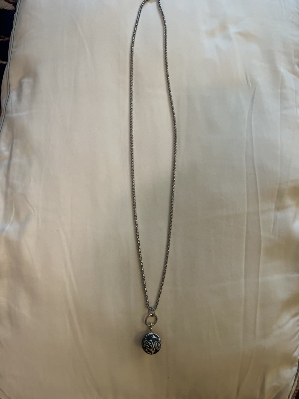 This Jilzarah necklace features a black and white patterned polymer clay bead pendant on a stainless steel chain.