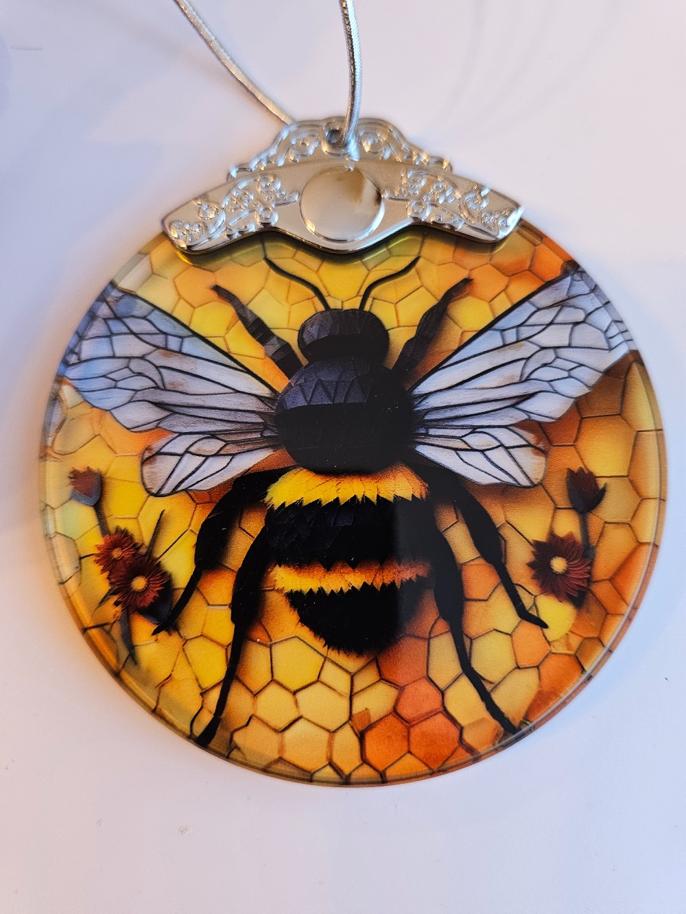 Round suncatcher featuring a black bumblebee against a yellow honeycomb background.