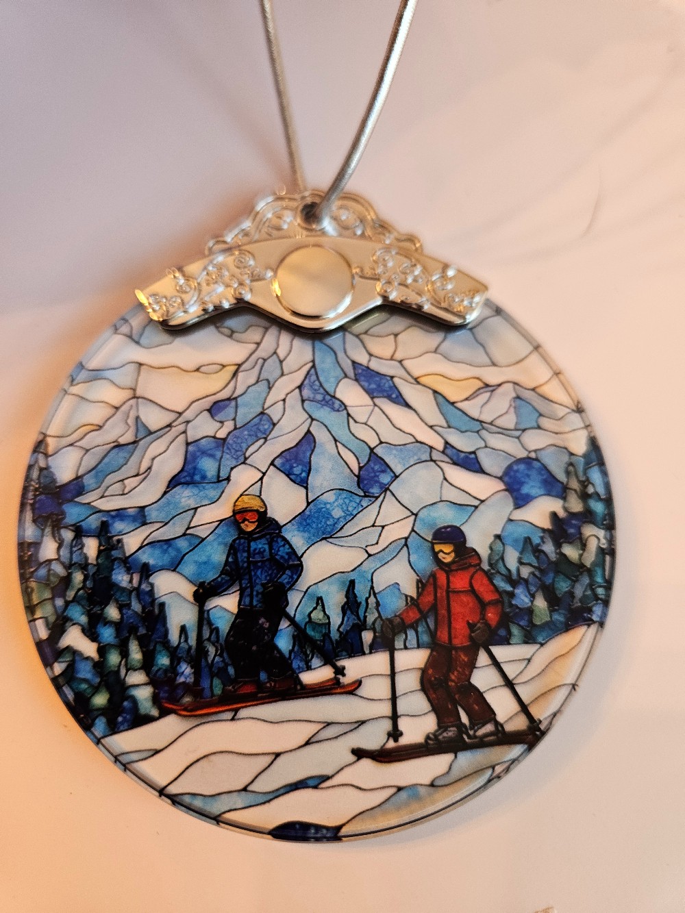 This Snowy Mountain Skiers Stained Glass Suncatcher features two skiers on a snowy mountain