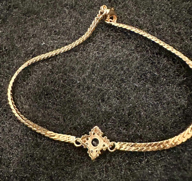 Gold tone herringbone bracelet with blue and clear crystal center