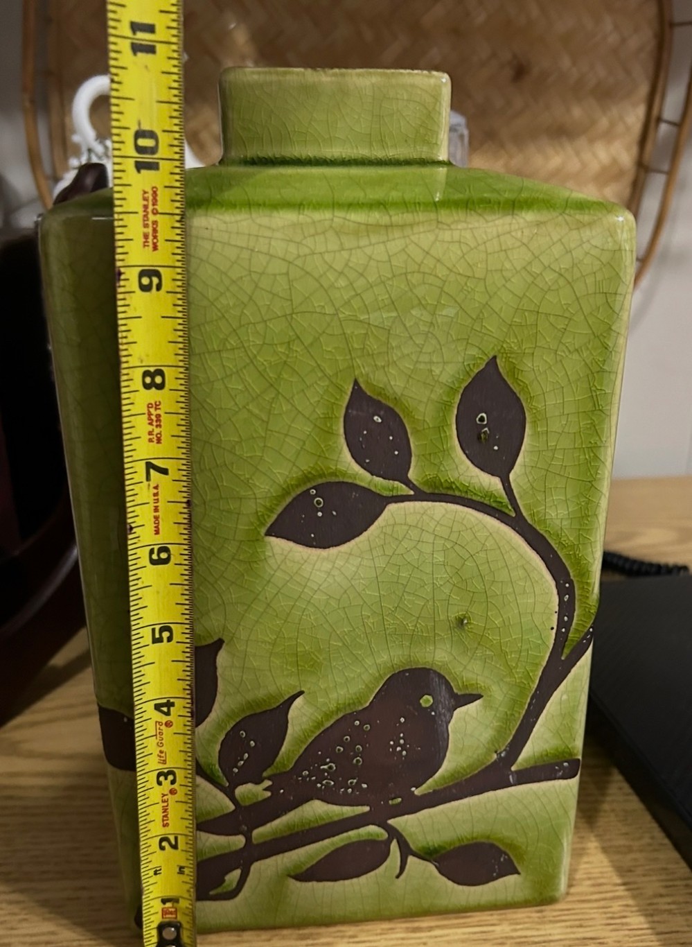 Green ceramic vase with a brown bird and branch motif