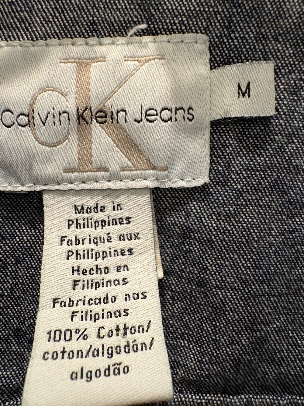 A Calvin Klein, jean jacket with a scrappy American flag on the back in a size medium