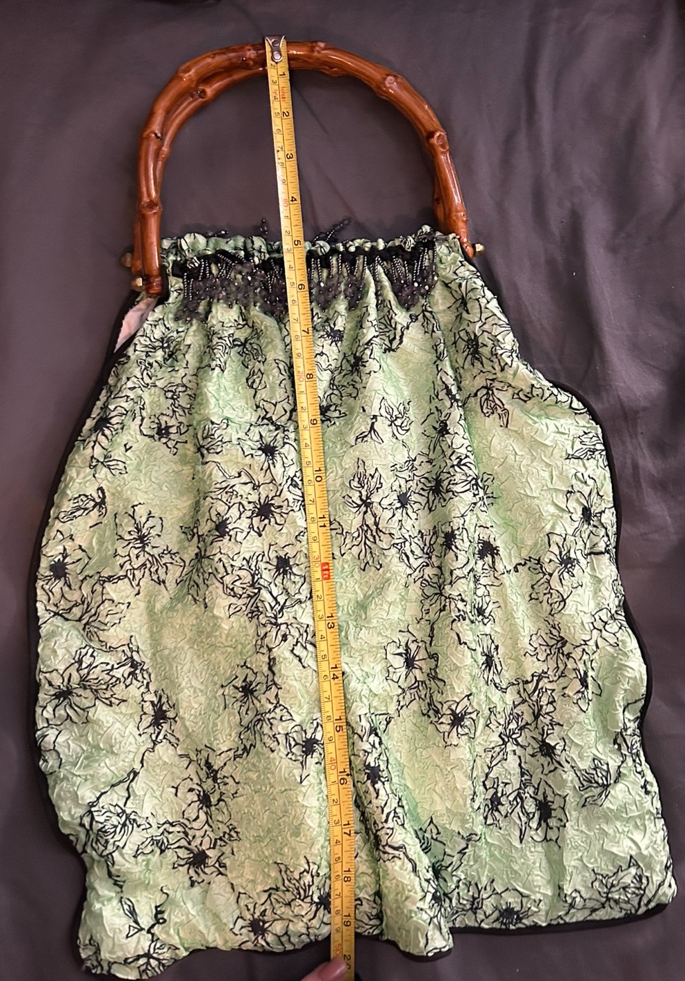 Bright green large purse with black design has black bead work and wood handles