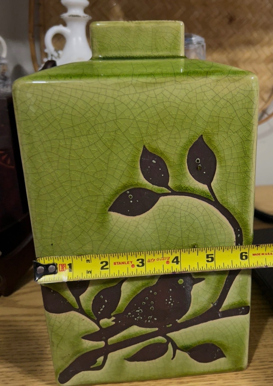 Green ceramic vase with a brown bird and branch motif