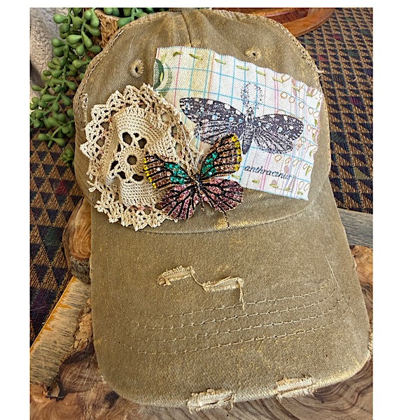 Hat: Gold brushed khaki distressed tucker hat w/doily, butterfly applique, blinged butterfly brooch