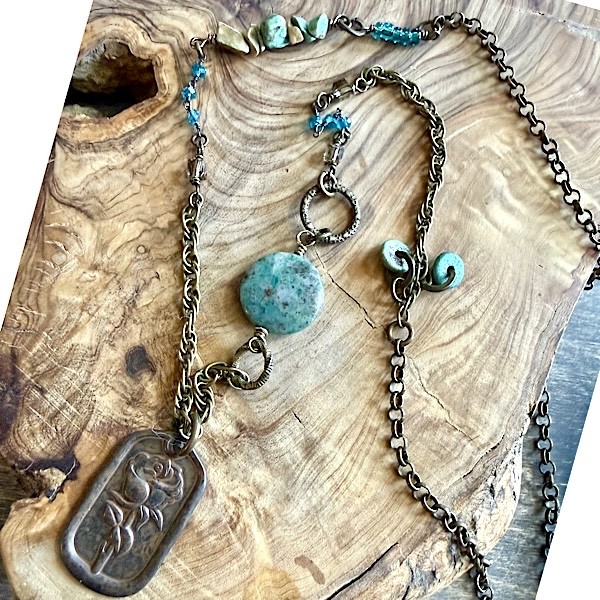 Rustic Rose embossed pendant on assembled mid-length bronze chain with beaded adornments in shades of greens/blues